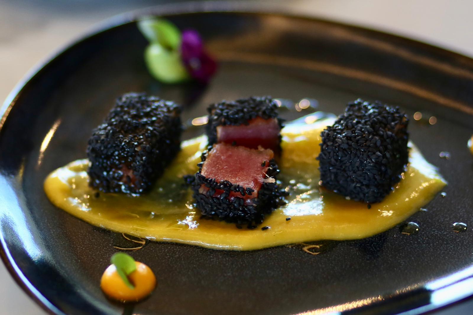 Octopus tentacle on roasted potatoes plated on dark ceramic